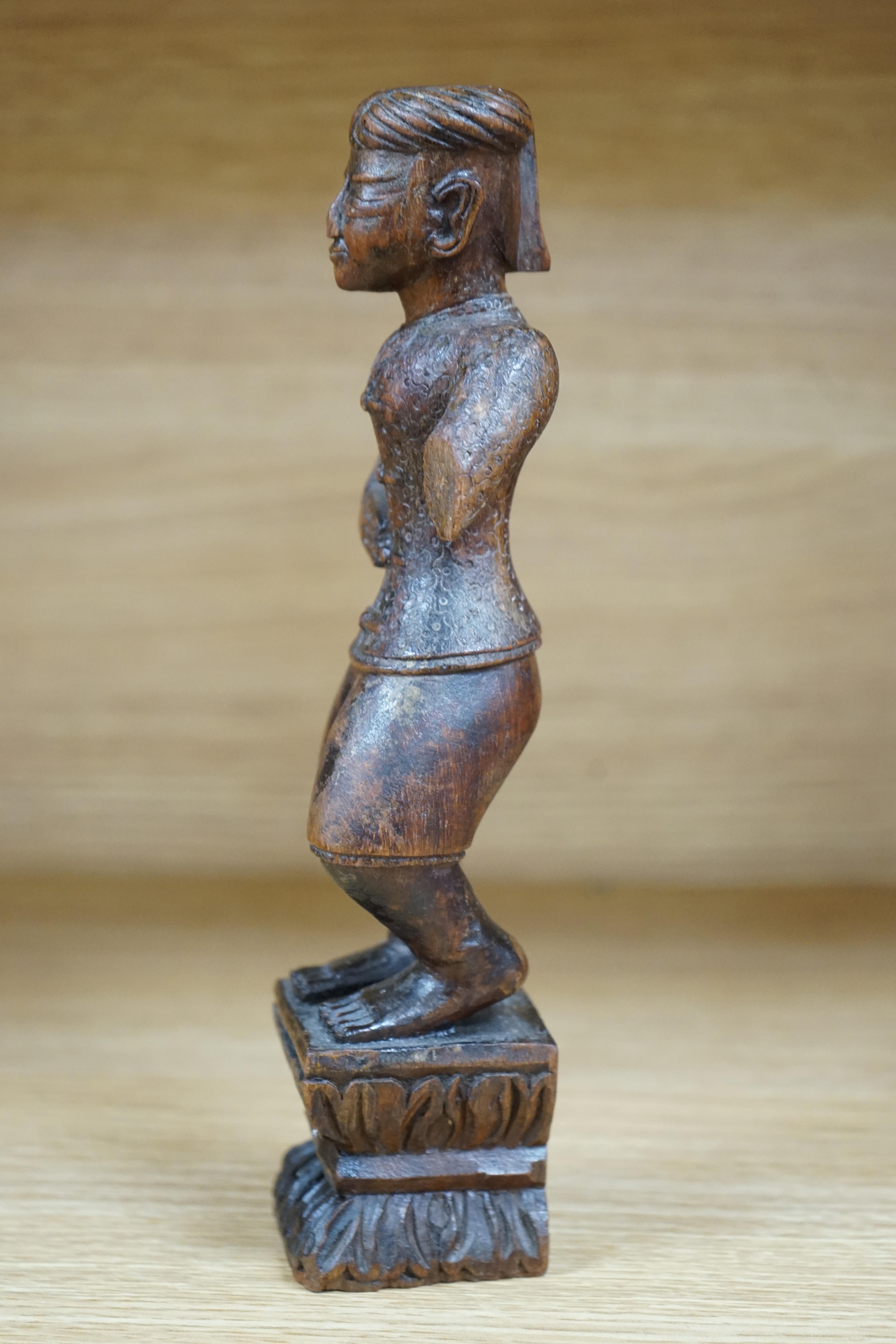 A 19th century Indian carved wood figure of a man, 23cm high. Condition - poor to fair, one arm missing